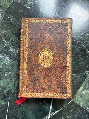 un vieux livre posé sur une table en marbre, à côté d'un ruban rouge