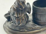 a figurine of a man sitting on a plate with a cup