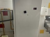 un réfrigérateur blanc dans une salle de bains équipée d'un lavabo et d'un miroir