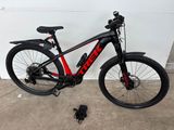 un vélo noir et rouge garé près d'un mur blanc