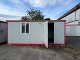 two white and red shipping containers with doors open in a parking lot