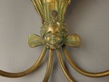 a gold wall clock with a face on the top of it