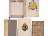 three old books are lined up on a white surface