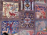 a person standing in front of a wall covered with colorful rugs