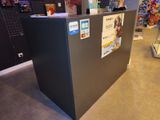un réfrigérateur noir dans un magasin, recouvert d'une multitude d'aimants