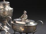 une théière en argent et une cuillère en argent posées sur une table