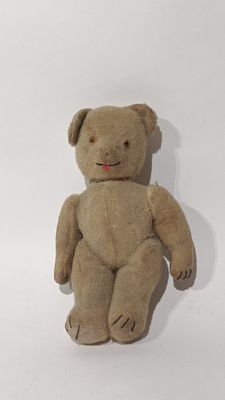 un ours en peluche marron assis sur une surface blanche