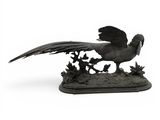 statue représentant un oiseau perché sur un rocher, avec un arbre en arrière-plan
