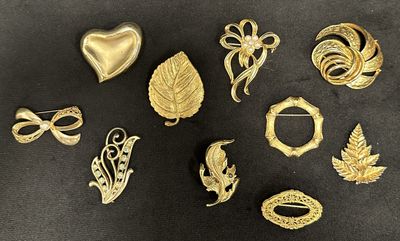 a lot of gold brooches and brooches on a black surface