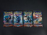 trois paquets de cartes à collectionner Pokémon posés sur une surface noire