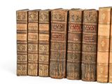 several old books are lined up in a row on a white surface