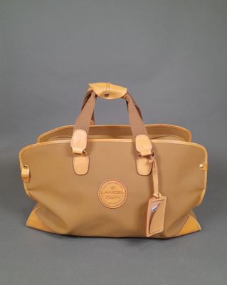 a tan leather handbag with two handles on a grey background