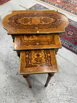 Trois tables en bois aux motifs complexes sont posées sur un tapis dans une pièce