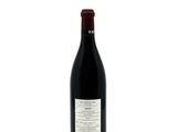 the bottle of red wine is sitting on a white surface