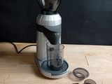 a coffee grinder sitting on a wooden table with a cup of coffee