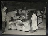 photographie en noir et blanc montrant des hommes travaillant sur une voiture dans un garage