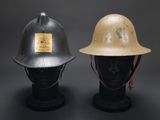 pair of british wwii era steel helmets on display against a black background