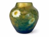 un vase vert orné de fleurs blanches, posé sur une surface blanche