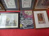 many framed pictures on a table with a red table cloth