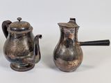 three antique silver teapots on a white surface with a black handle