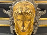 a black and gold vase with a gold face on it