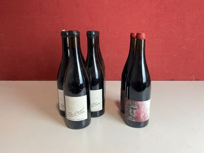 trois bouteilles de vin sont posées sur une table devant un mur rouge