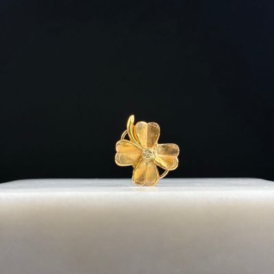 a close up of a gold flower ring on a white surface
