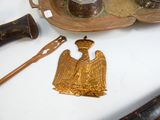 a gold plate with a bird on it next to a knife and other items