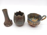 three pieces of pottery sitting next to each other on a white surface
