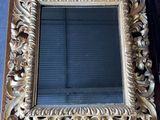 un miroir au cadre doré ouvragé posé sur une table en bois dans une pièce
