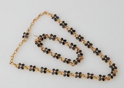 a close up of a necklace and bracelet on a white surface