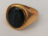 an image of a gold signet ring with a black stone in the center