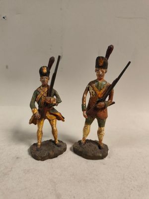 deux figurines de soldats armés et en uniforme, posées sur une surface blanche
