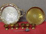 deux plateaux en argent et des tasses à anse posés sur une nappe rouge