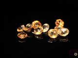 a close up of a pair of yellow sapphires on a black surface