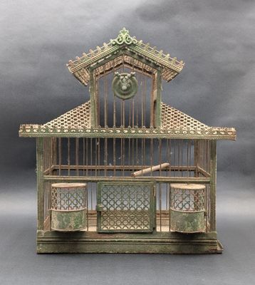 a small bird cage with a bell on top of it