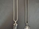 two silver necklaces with a shark tooth pendant on a black leather surface