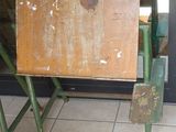 une vieille table en bois avec un pied en métal, placée devant une porte