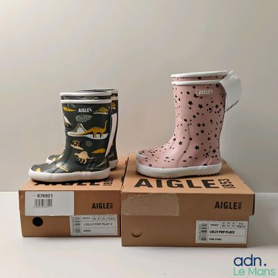 deux bottes de pluie pour enfants posées sur des cartons, sur une table