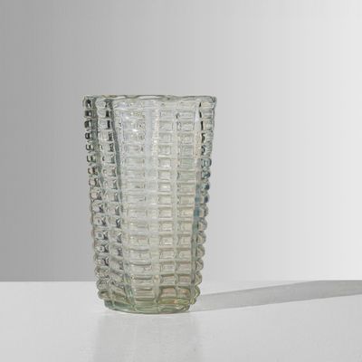 un vase en verre posé sur une table, sur fond blanc