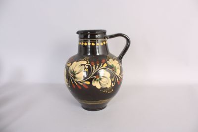 un vase noir et or posé sur une surface blanche