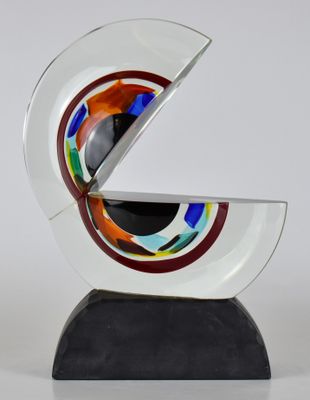 une image représentant une sculpture en verre ornée d'un motif circulaire posée sur un socle noir