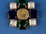 an image of a brooch with pearls and gems on a blue background