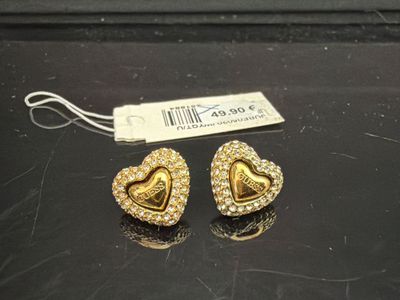 une paire de boucles d'oreilles en or en forme de cœur posées sur un fond noir