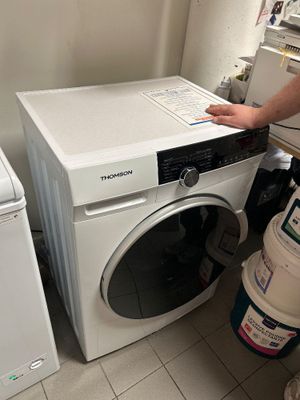 un homme debout à côté d'un lave-linge et d'un sèche-linge