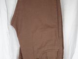 un pantalon marron suspendu à un cintre sur un drap blanc