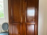 a wooden armoire in the corner of a room with a blue chair