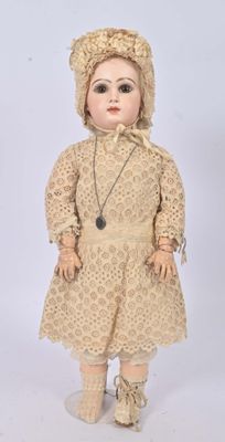 an old doll with a hat and dress is standing on a white surface