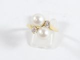 un gros plan d'une bague ornée de deux perles sur un fond blanc