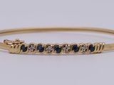 un bracelet rigide en or jaune serti de saphirs bleus